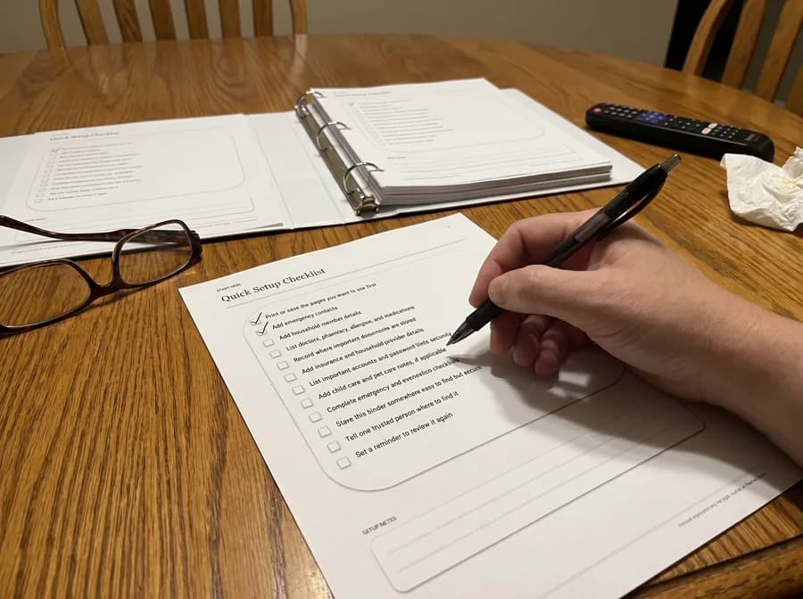 A hand filling in the printed Quick Setup Checklist page with a pen