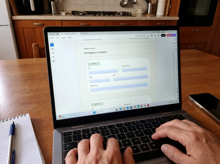 The fillable Emergency Binder PDF open in Adobe Acrobat on a laptop at a kitchen table