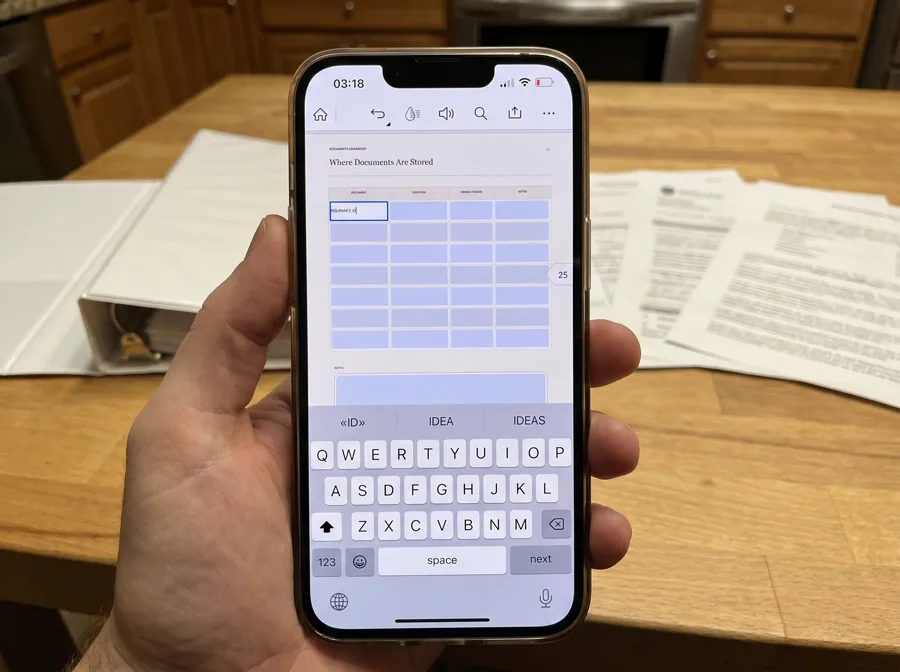 A hand holding a phone with the fillable Emergency Binder PDF open in the Acrobat mobile app